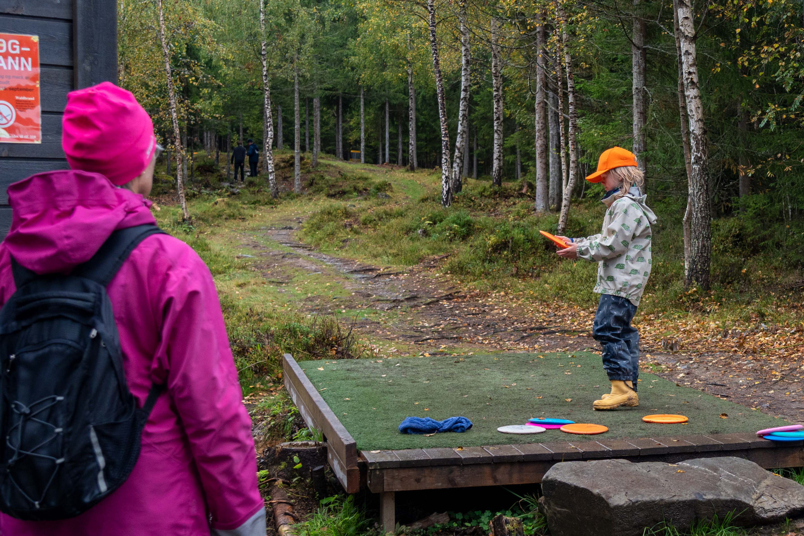 Barn kaster frisbee på en frisbeegolfbane.