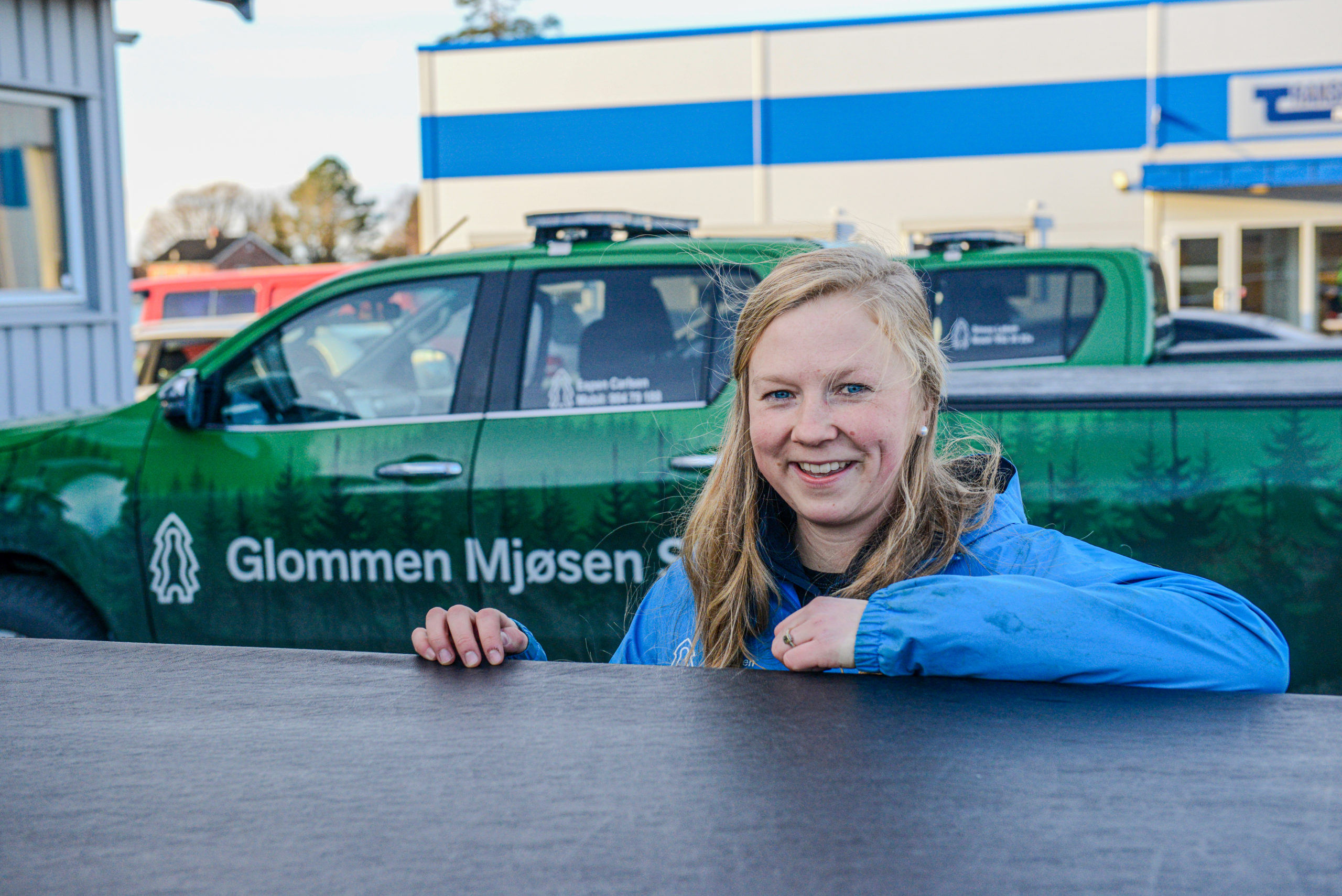 Kari Hunstad Mørck med Glommen Mjøsen Skog-bil i bakgrunnen.