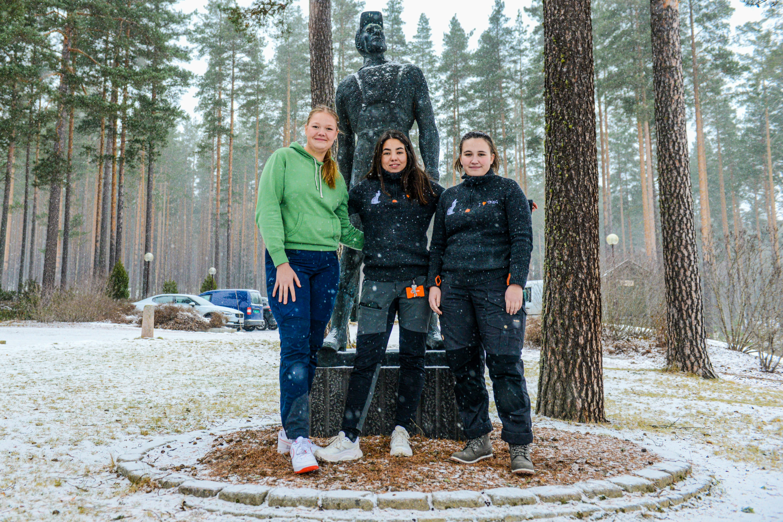 Tre unge kvinner ved en statue.