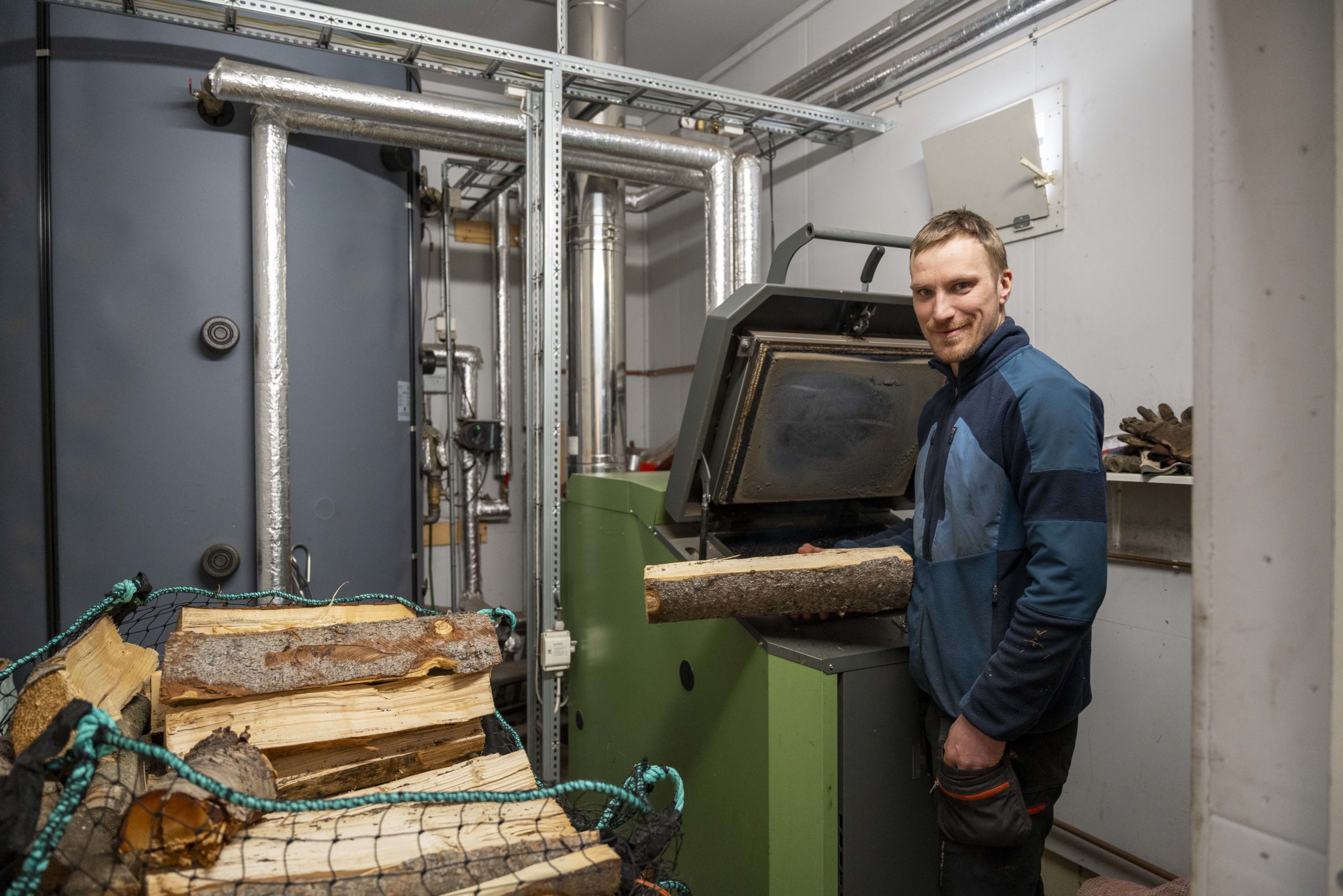 Erik Nesteby legger en vedskive i et fyringsanlegg.