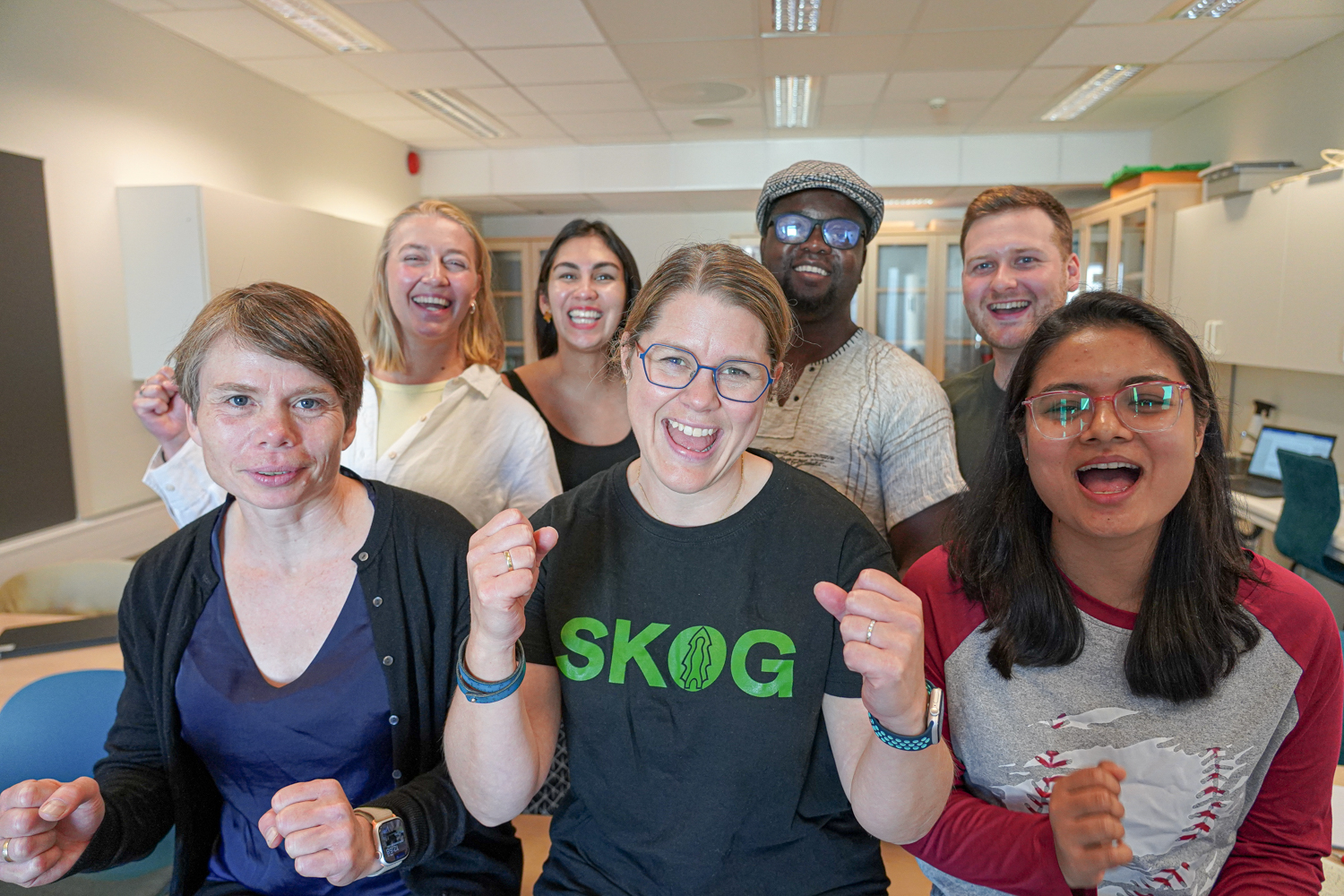 Sju glade personer med knyttede never.