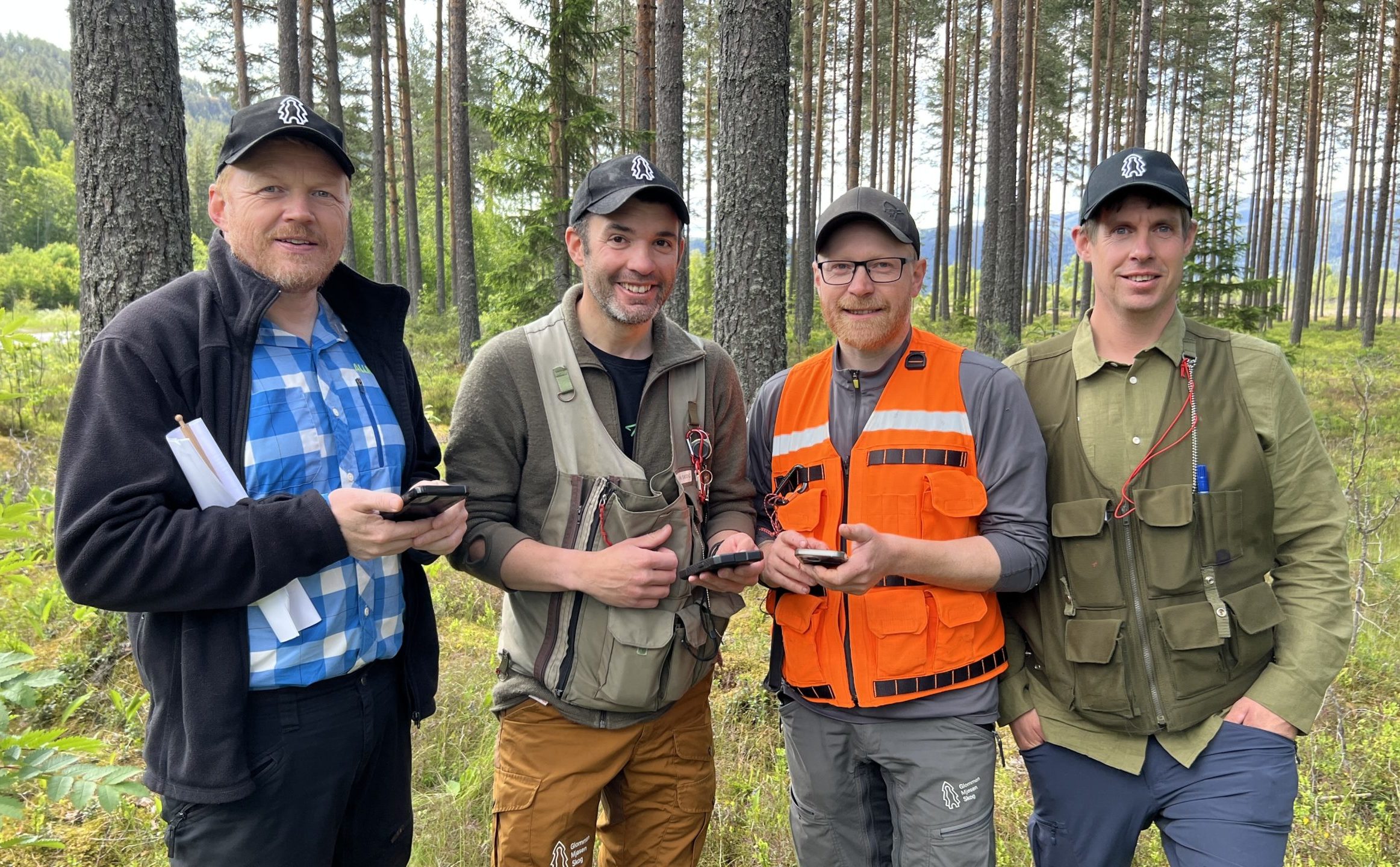 Fire menn i skogen, tre av dem vester skogbruksplanleggere bruker.
